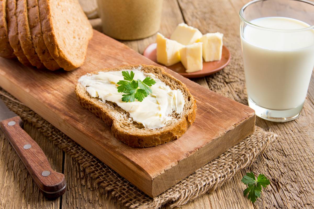 Frühstückstisch mit Butterbrot, Butter und Glas Milch