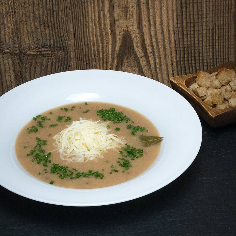 Eine Schüssel mit Brennsuppe, darauf geriebener Bergkäse und Schnittlauch, daneben Brotwürfel in einer gesonderten Schüssel