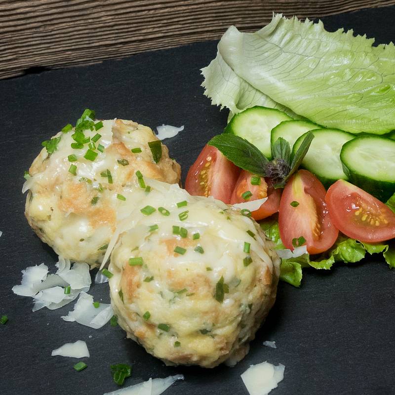 Zwei Käseknödel neben einem Salat