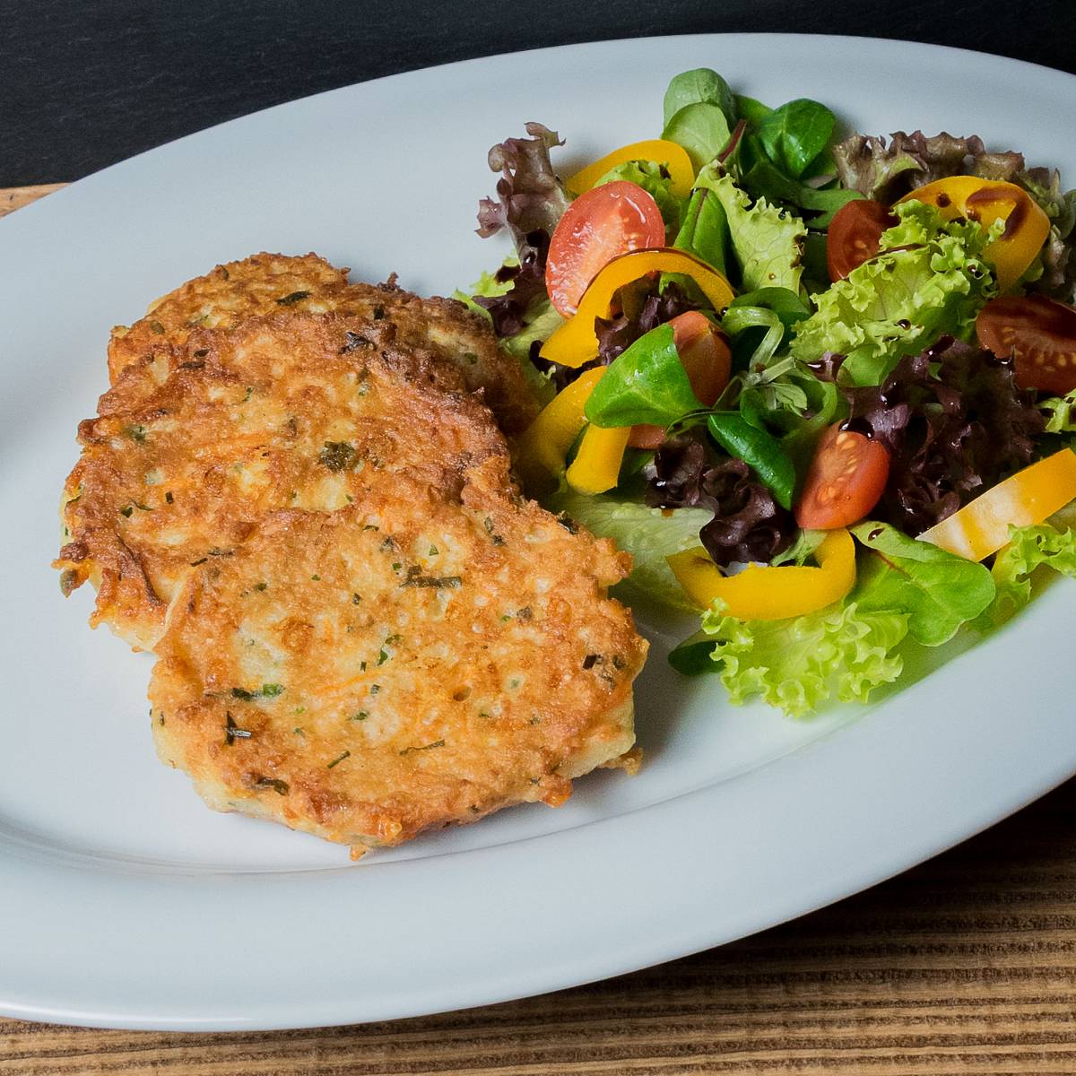 Ein Käse-Gemüse-Schnitzel auf einem Teller mit buntem Salat