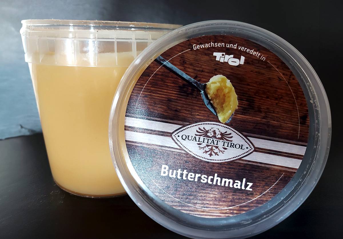 Butterschmalz der Käserei in einer geöffneten Eimer-Verpackung und daneben der Deckel
